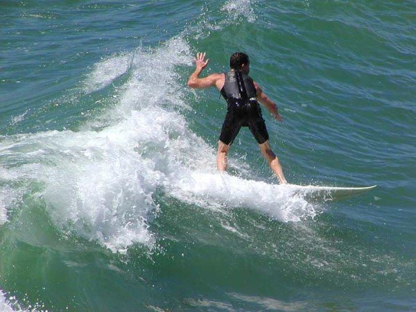 A surfer enjoys the fine weather and good surfing conditions as he catches a wave.